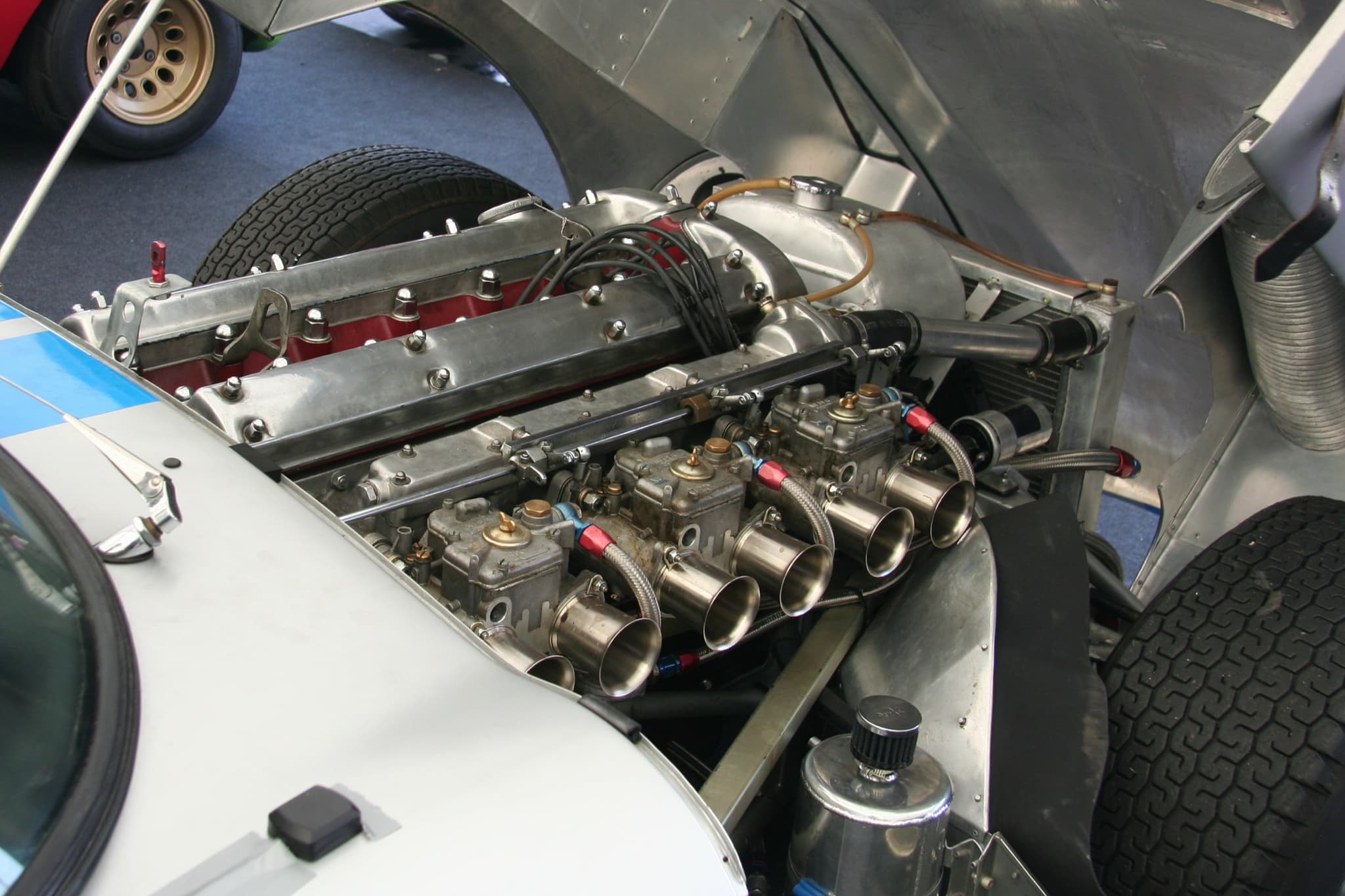 A racing E-Type's six-cylinder engine fitted with three twin-choke Weber carburettors and polished trumpets.
