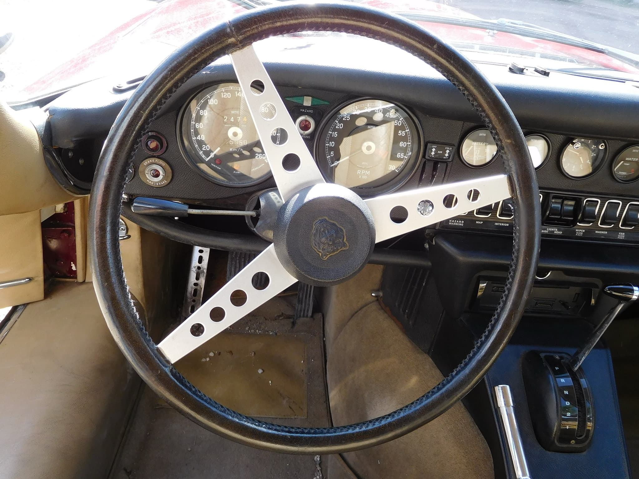 Close view of an E-Type's leather-rim wheel and dials, with an automatic gear selector on the console.