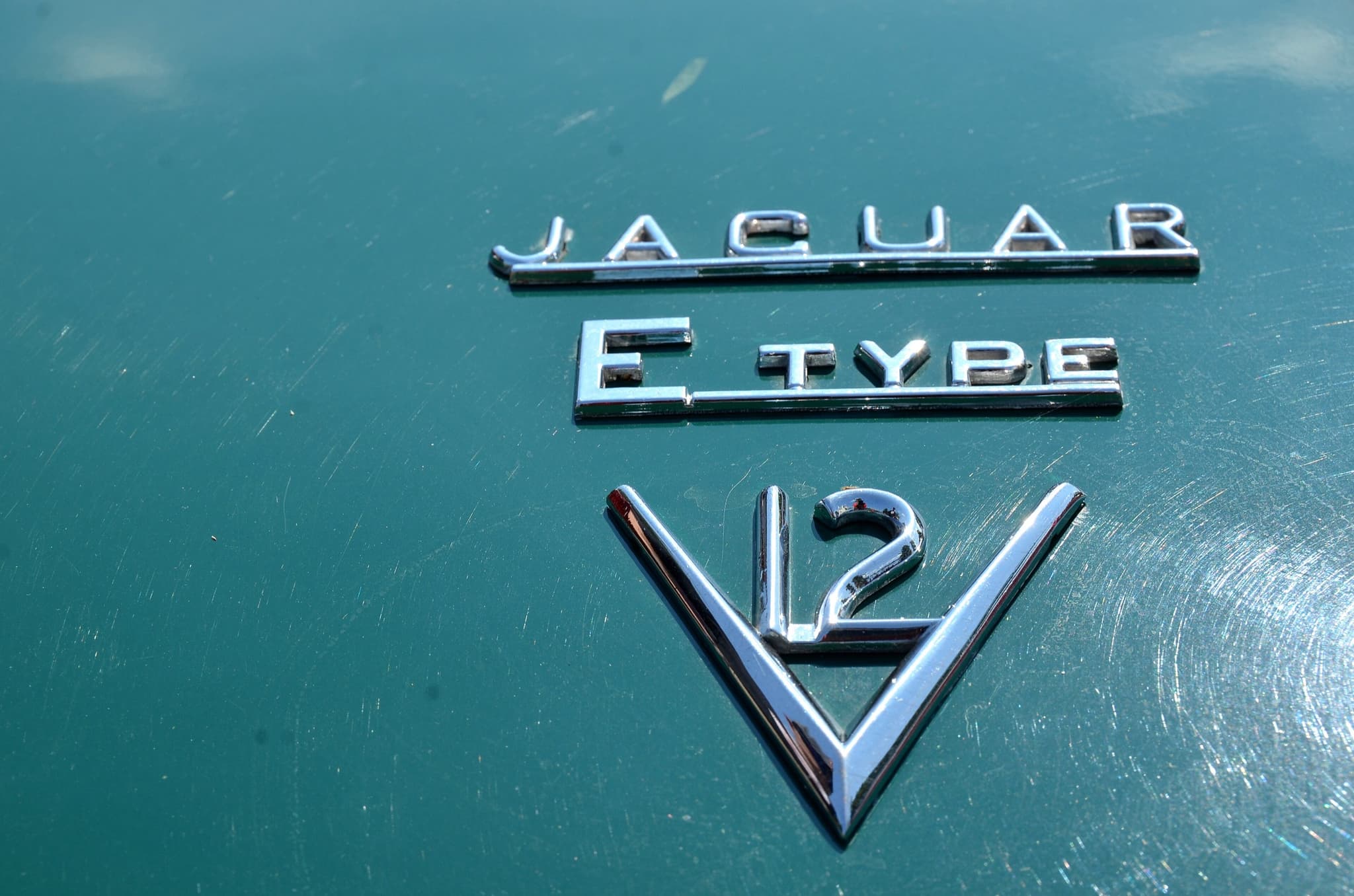 Chrome 'JAGUAR', 'E TYPE' and 'V12' badges on a teal boot lid.