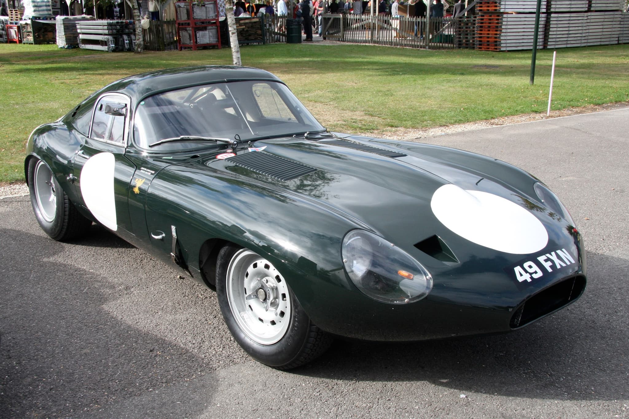 A dark green low-drag E-Type coupé with white roundels and the registration 49 FXN on tarmac. Opens a larger view