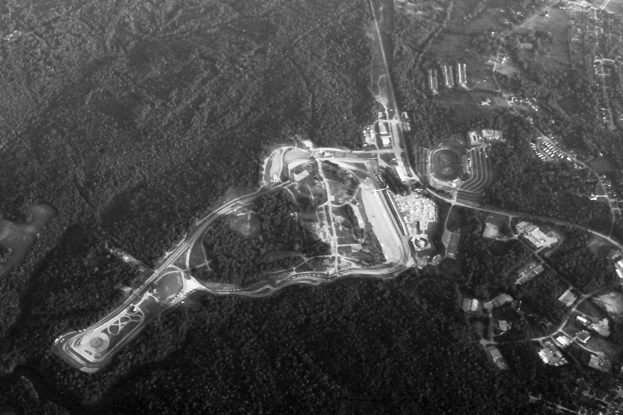 An aerial view of a winding racing circuit among woods.