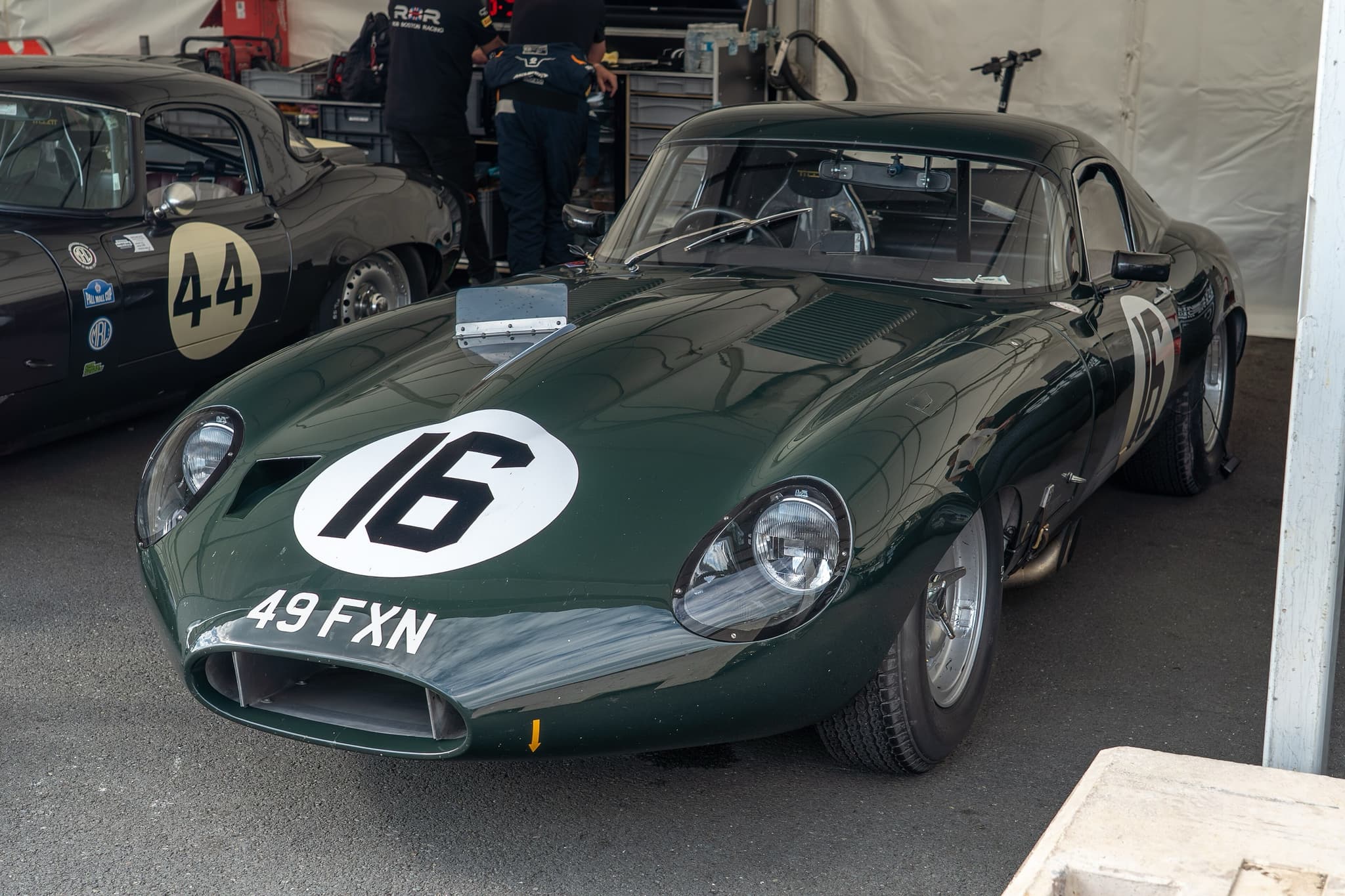 A dark green low-drag E-Type coupé numbered 16 with the registration 49 FXN in a paddock tent.